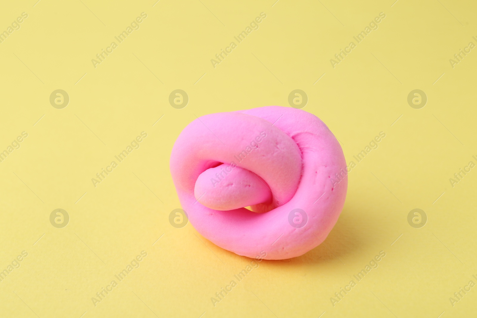 Photo of Bright pink play dough on yellow background