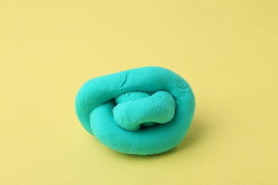 Photo of Bright turquoise play dough on yellow background, closeup