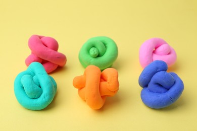 Photo of Different colorful play dough on yellow background, closeup