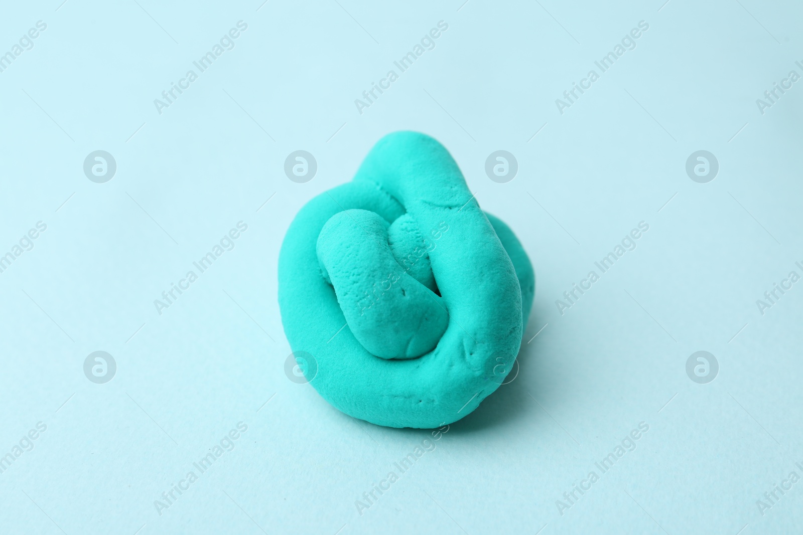 Photo of Turquoise play dough on light blue background, closeup