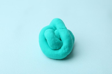 Photo of Turquoise play dough on light blue background, closeup