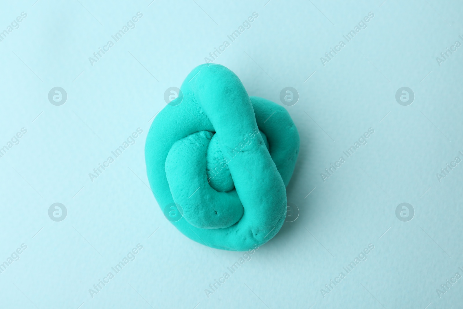 Photo of Turquoise play dough on light blue background, top view