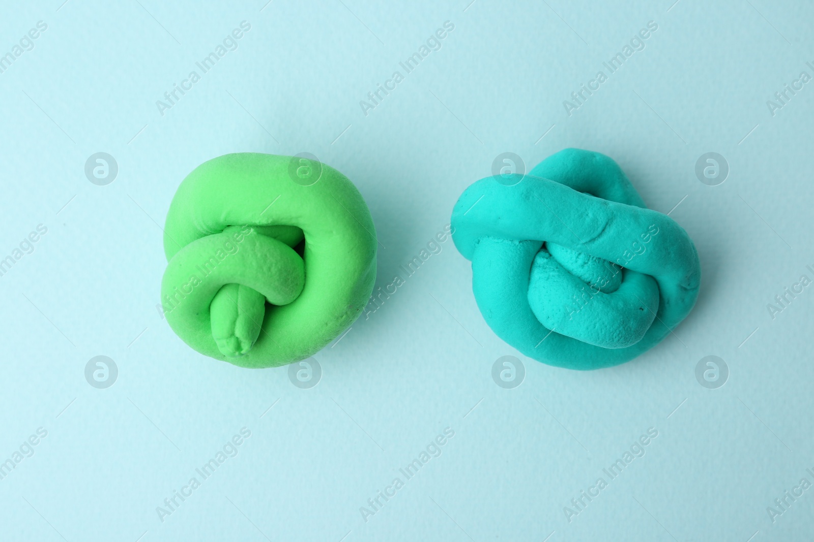 Photo of Colorful play dough on light blue background, top view