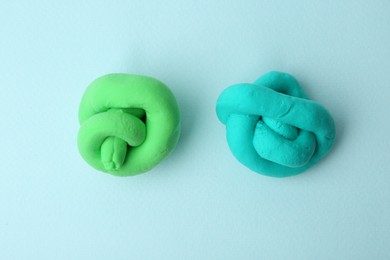 Photo of Colorful play dough on light blue background, top view