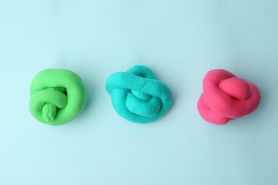 Photo of Different colorful play dough on light blue background, flat lay