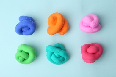 Photo of Different colorful play dough on light blue background, flat lay