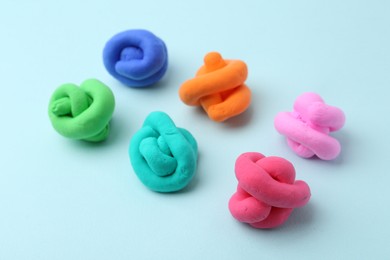 Photo of Different colorful play dough on light blue background, closeup