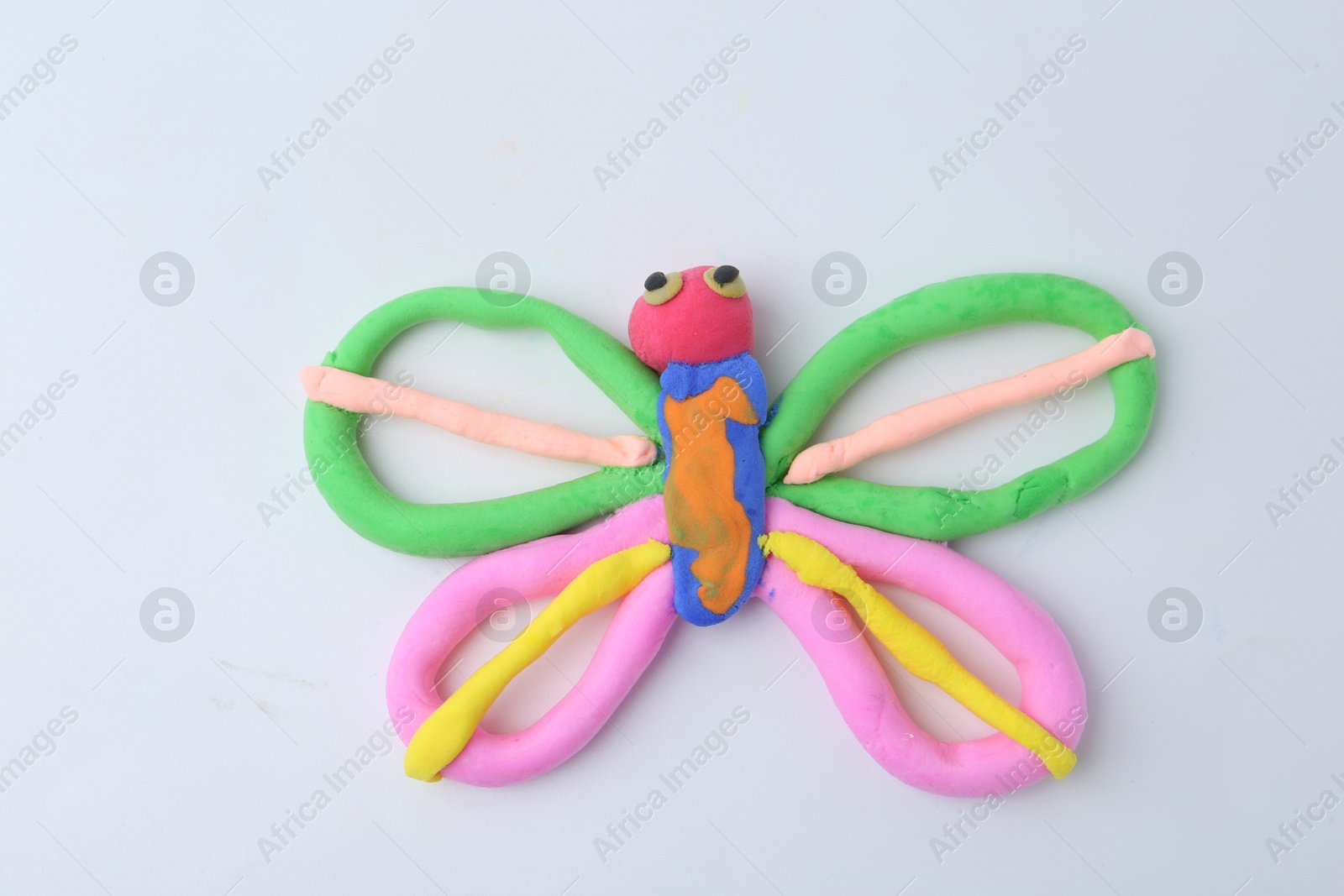 Photo of Butterfly made from play dough on white background, top view