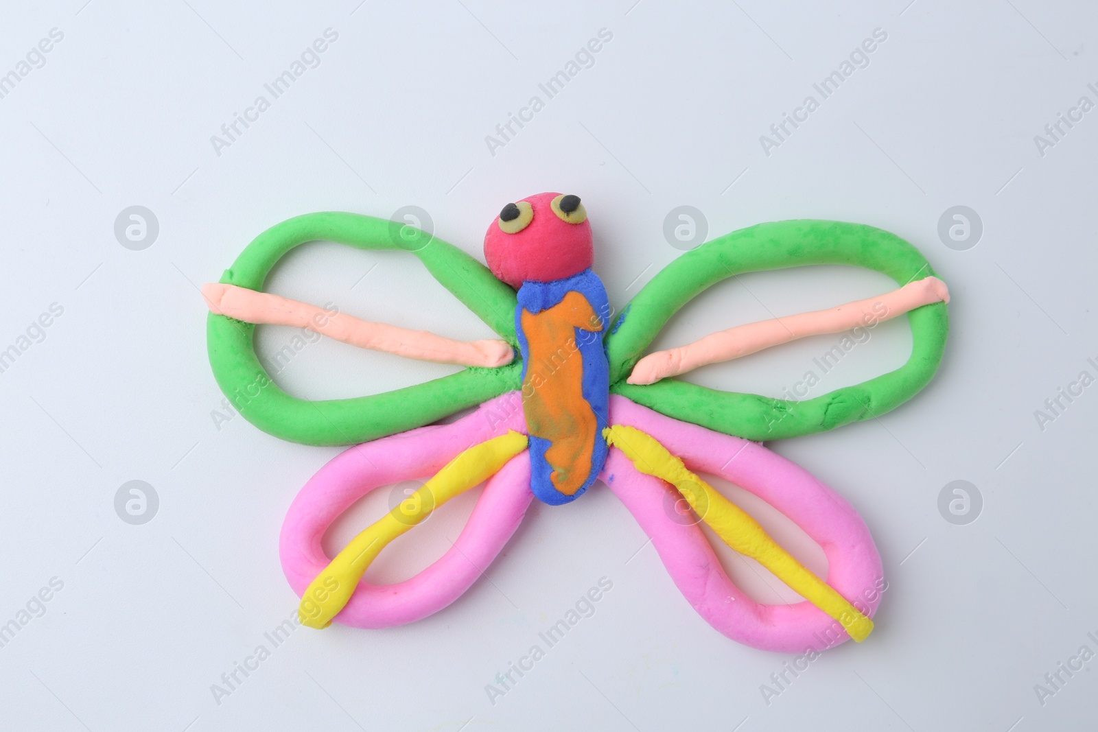 Photo of Butterfly made from play dough on white background, top view