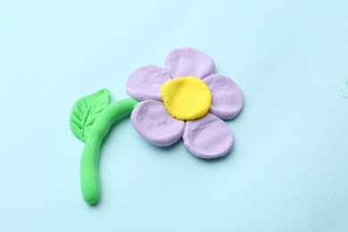 Photo of Flower made from play dough on light blue background, above view