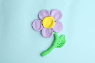 Photo of Flower made from play dough on light blue background, top view