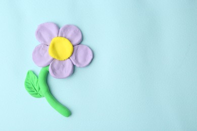 Photo of Flower made from play dough on light blue background, top view. Space for text