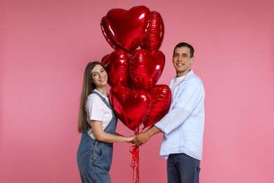 Photo of Lovely couple with heart shaped balloons on pink background. Valentine's day celebration