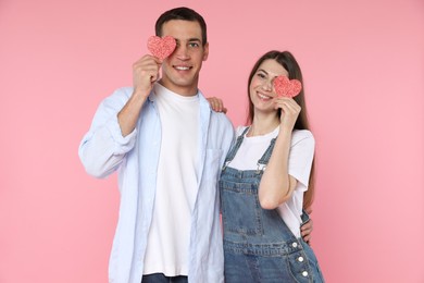 Photo of Lovely couple with paper hearts on pink background. Valentine's day celebration