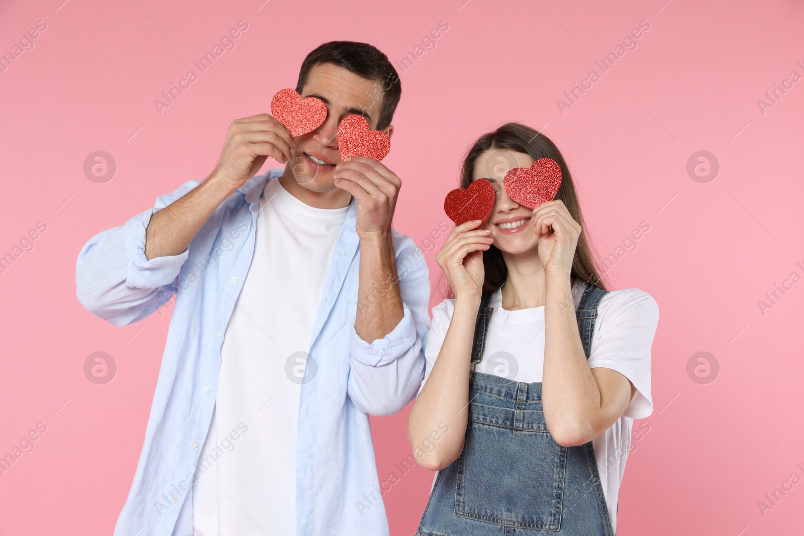 Photo of Lovely couple with paper hearts on pink background. Valentine's day celebration