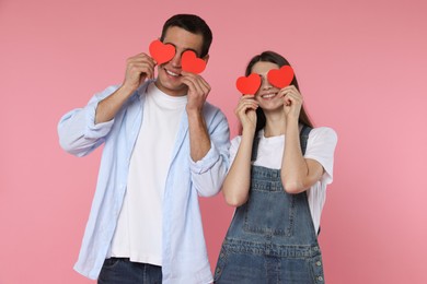 Photo of Lovely couple with paper hearts on pink background. Valentine's day celebration