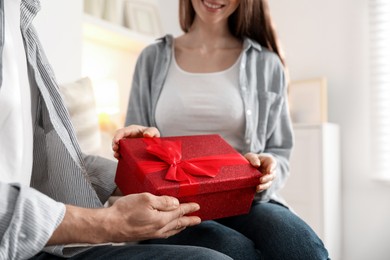 Photo of Lovely couple with gift box indoors, closeup. Valentine's day celebration