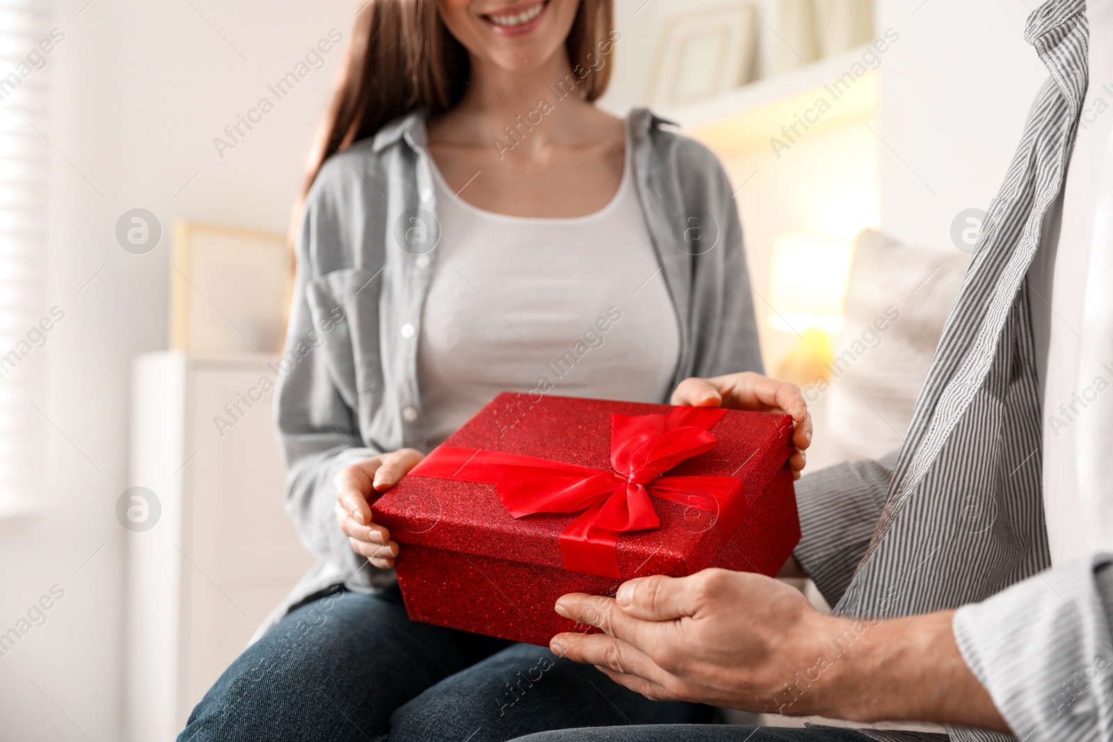 Photo of Lovely couple with gift box indoors, closeup. Valentine's day celebration