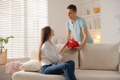 Lovely man surprising his girlfriend with Valentine's day gift indoors