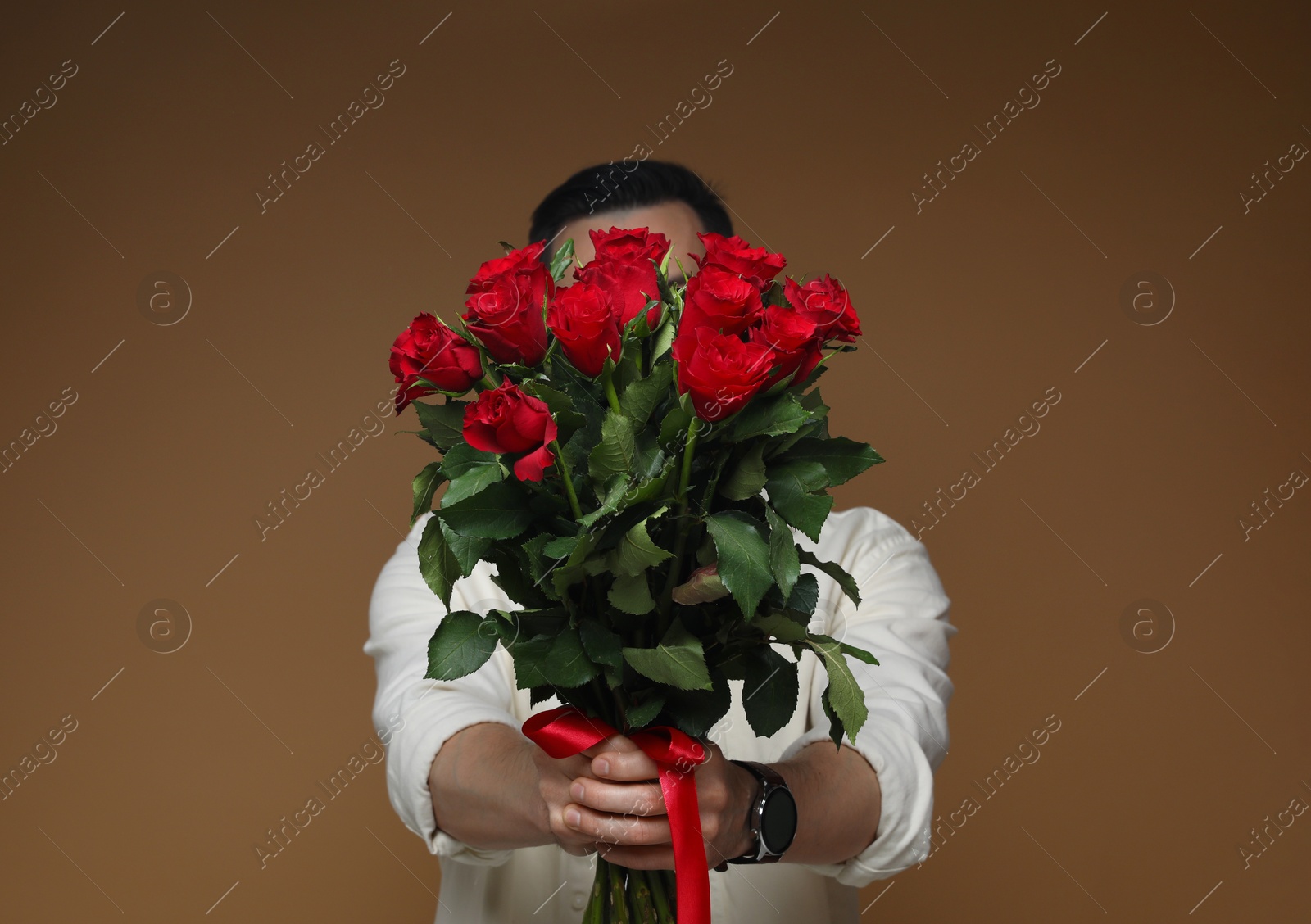 Photo of Happy Valentine's Day. Man with bouquet of roses on brown background