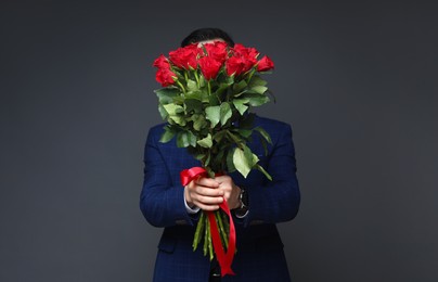 Photo of Happy Valentine's Day. Man with bouquet of roses on grey background