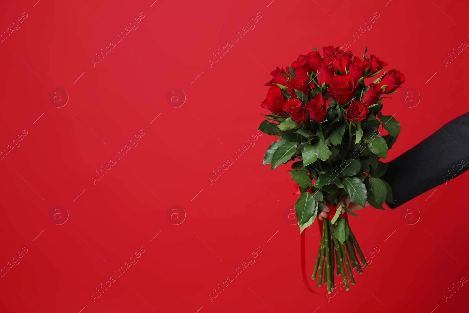 Photo of Happy Valentine's Day. Man with bouquet of roses on red background, closeup. Space for text