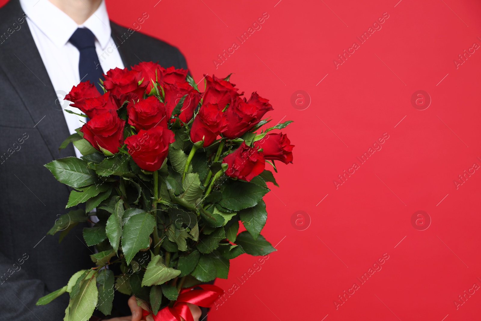 Photo of Happy Valentine's Day. Man with bouquet of roses on red background, closeup. Space for text