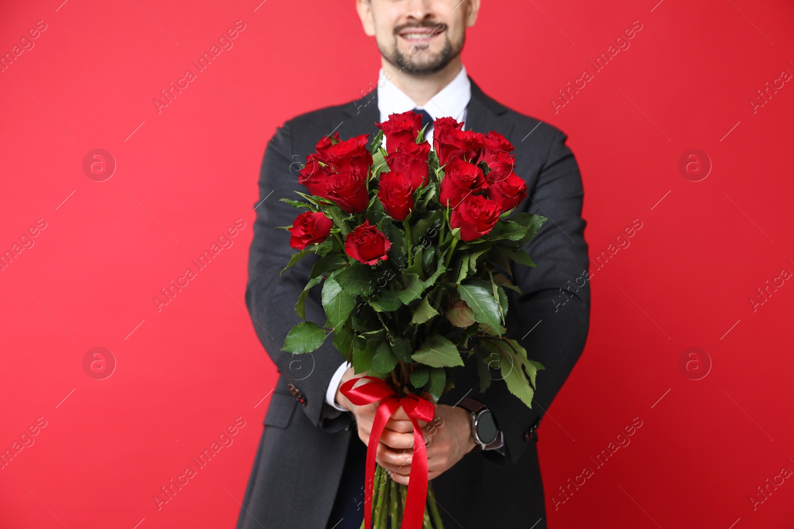 Photo of Happy Valentine's Day. Man with bouquet of roses on red background, closeup