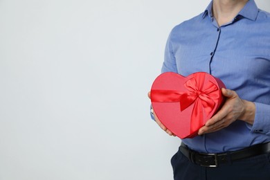 Photo of Happy Valentine's Day. Man with heart shaped gift box on white background, closeup. Space for text