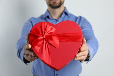 Photo of Happy Valentine's Day. Man with heart shaped gift box on white background, closeup