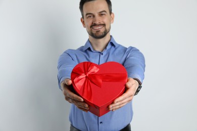 Photo of Happy Valentine's Day. Handsome man with heart shaped gift box on white background, selective focus