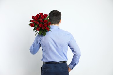 Photo of Happy Valentine's Day. Man with bouquet of roses on white background, back view