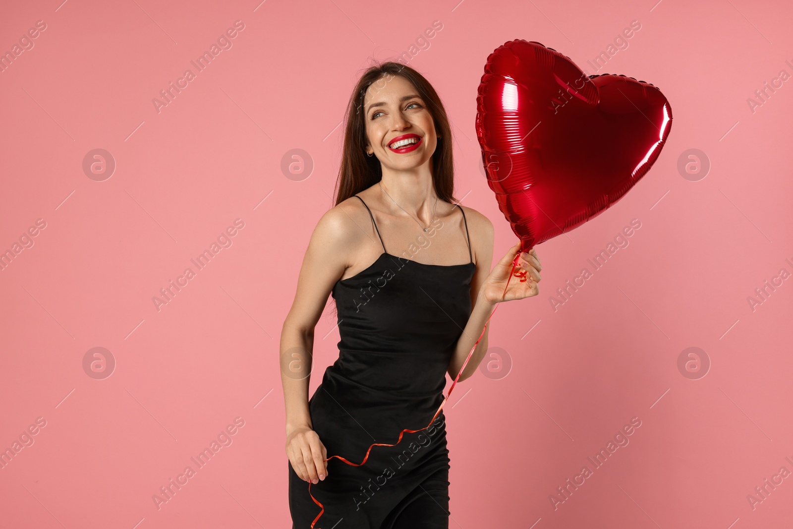 Photo of Happy Valentine's Day. Beautiful woman with heart shaped balloon on pink background