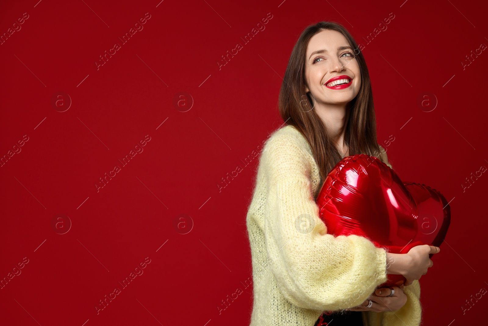 Photo of Happy Valentine's Day. Beautiful woman with heart shaped balloon on red background. Space for text