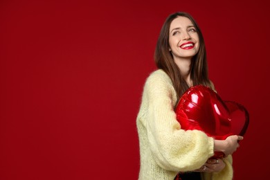 Photo of Happy Valentine's Day. Beautiful woman with heart shaped balloon on red background. Space for text