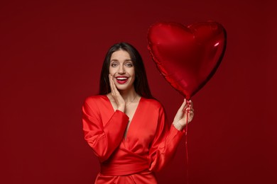 Happy Valentine's Day. Beautiful woman with heart shaped balloon on red background