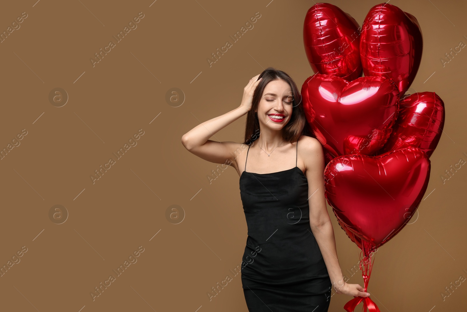 Photo of Happy Valentine's Day. Beautiful woman with heart shaped balloons on brown background. Space for text