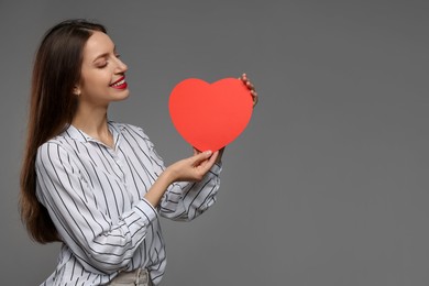 Photo of Happy Valentine's Day. Beautiful woman with paper heart on grey background. Space for text