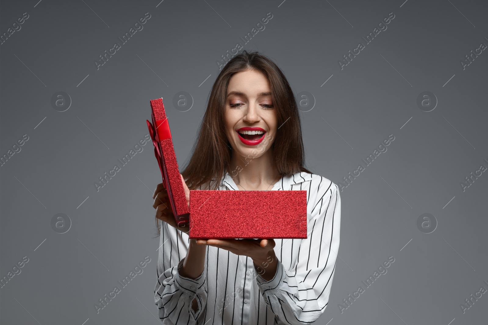 Photo of Happy Valentine's Day. Woman opening gift on grey background