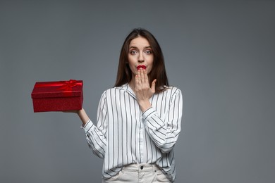 Photo of Happy Valentine's Day. Surprised woman with gift on grey background