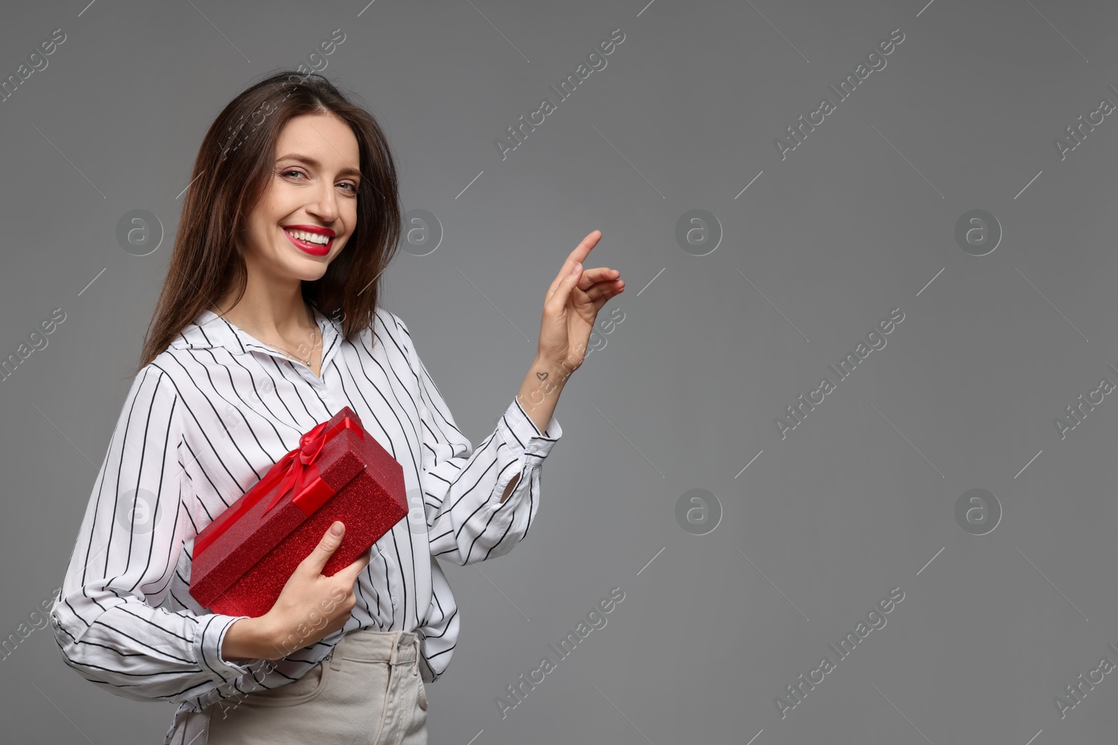 Photo of Happy Valentine's Day. Beautiful woman with gift on grey background. Space for text