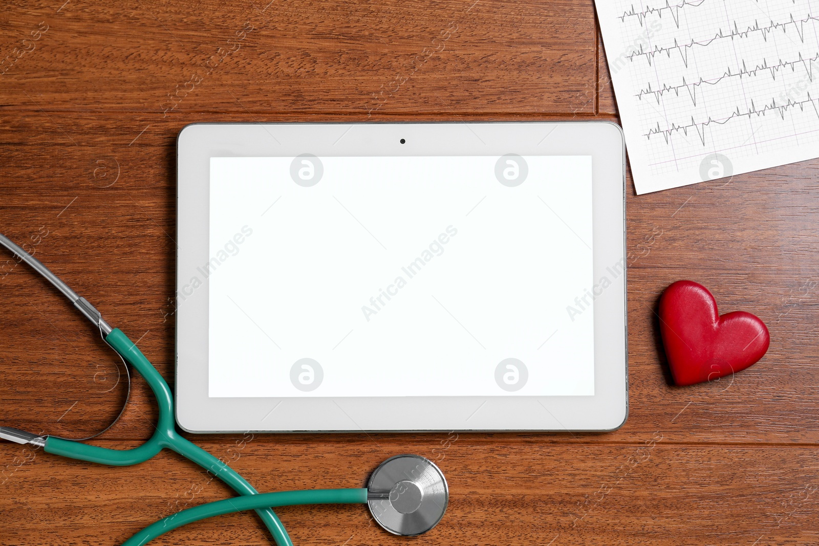 Photo of Cardiology. Tablet, cardiogram, stethoscope and red decorative heart on wooden table, flat lay