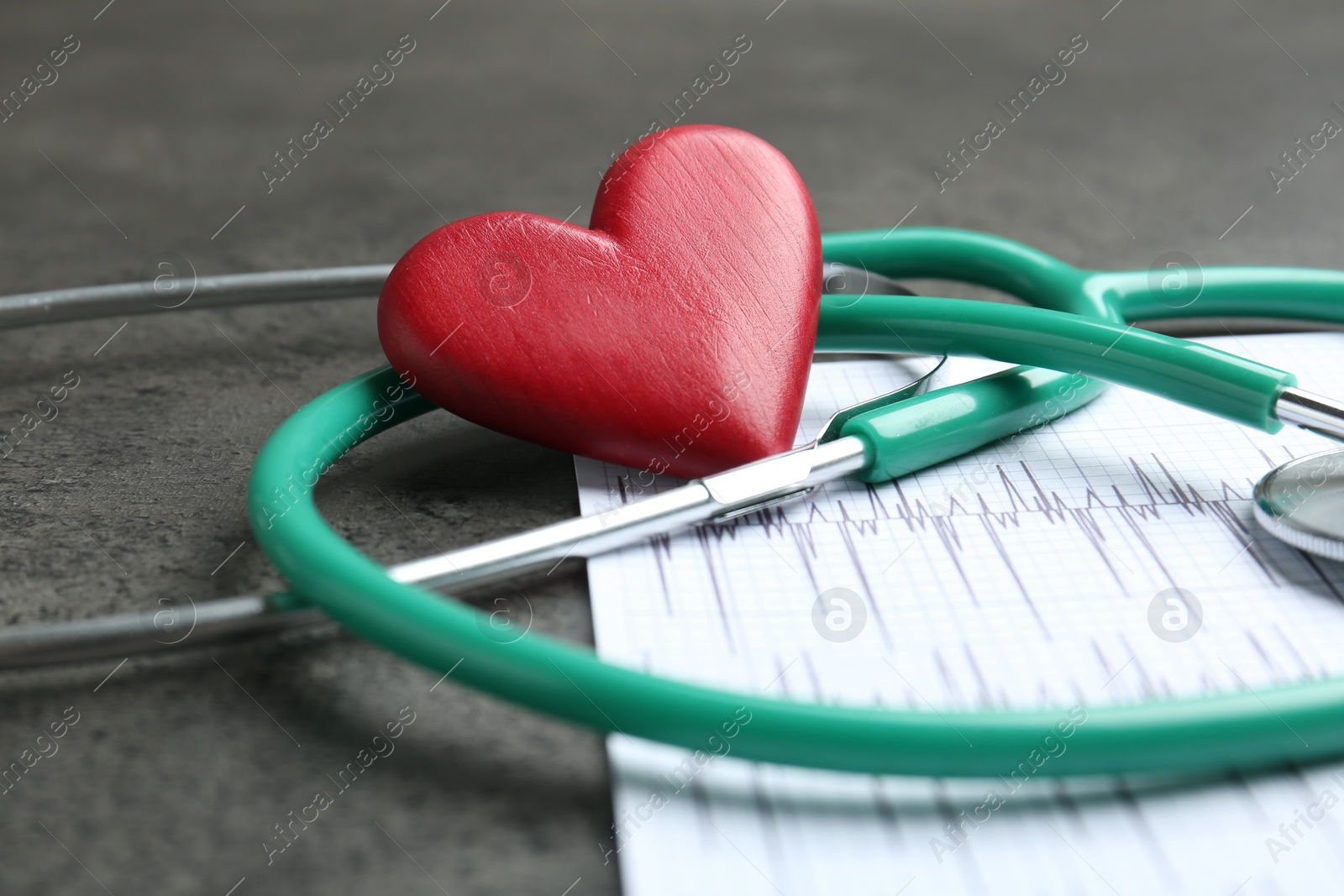 Photo of Cardiology. Cardiogram, stethoscope and red decorative heart on gray textured table, closeup