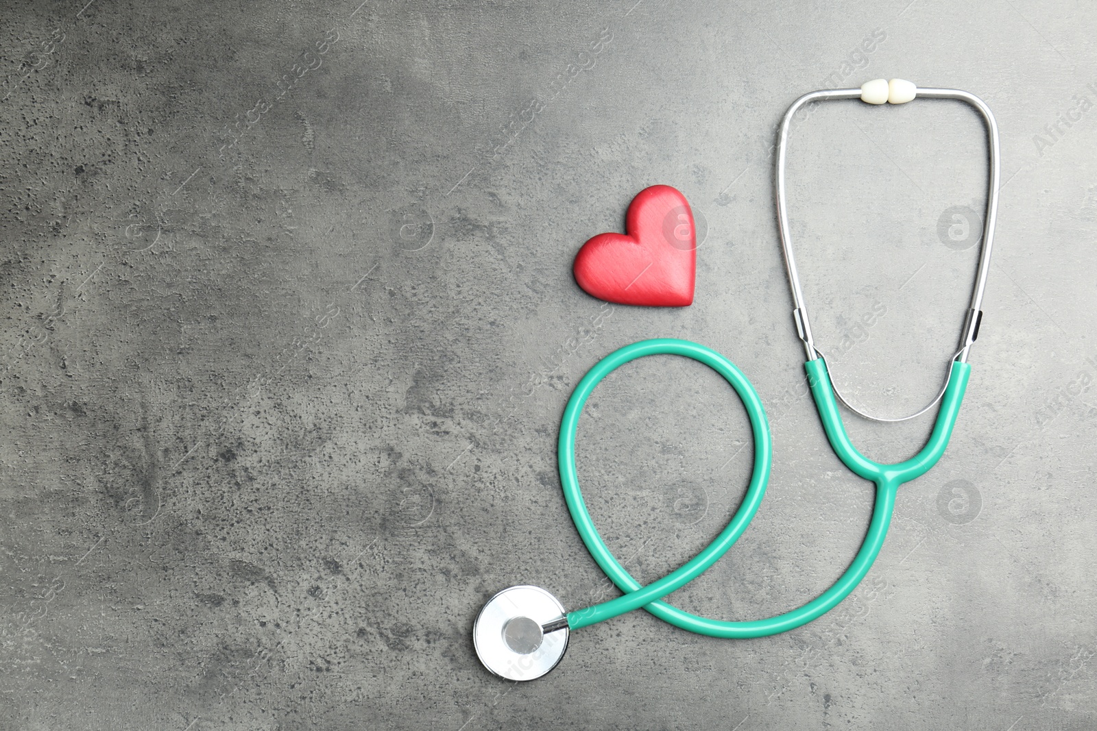 Photo of Cardiology. Stethoscope and red decorative heart on gray textured background, flat lay. Space for text