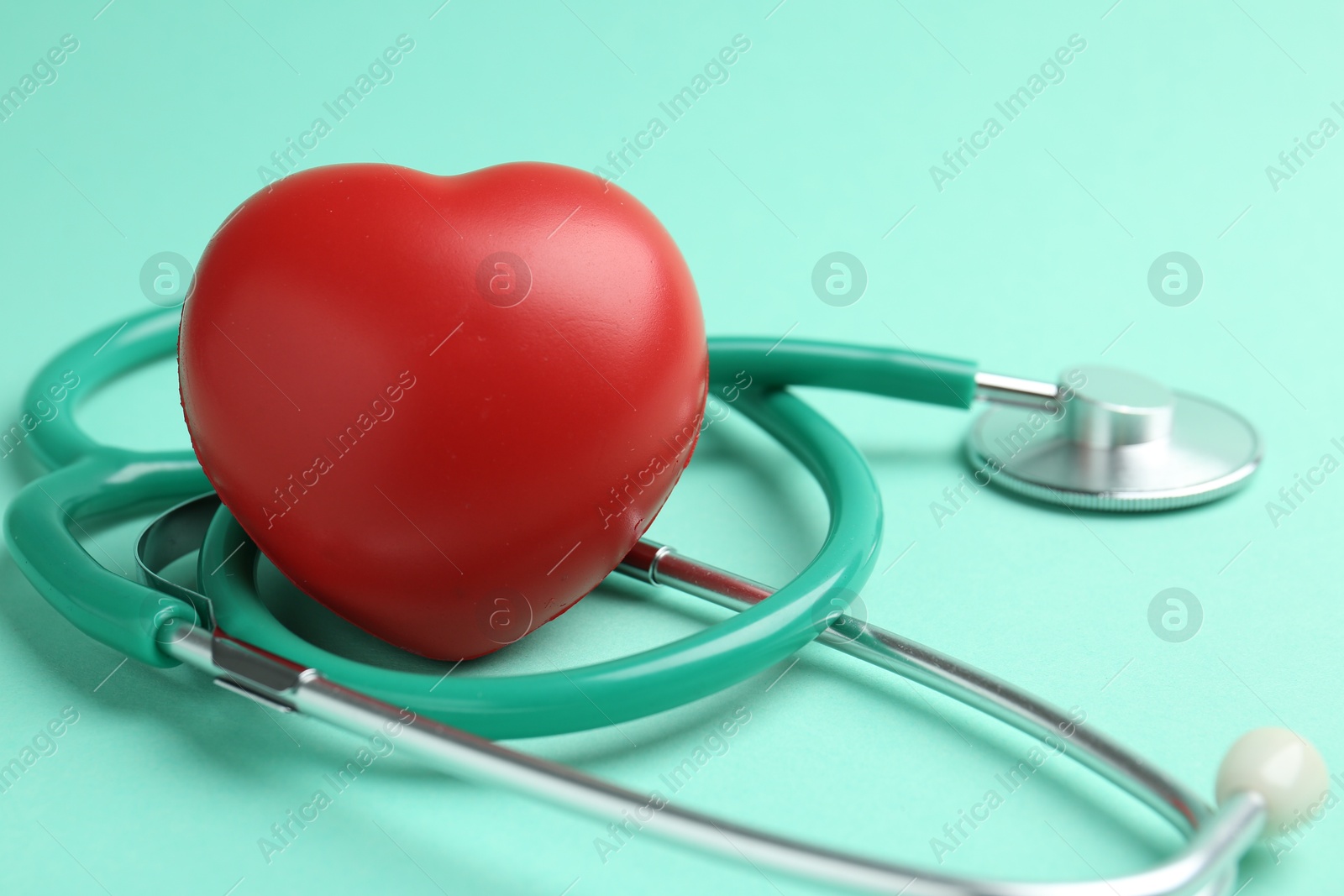 Photo of Cardiology. Stethoscope and red decorative heart on turquoise background, closeup