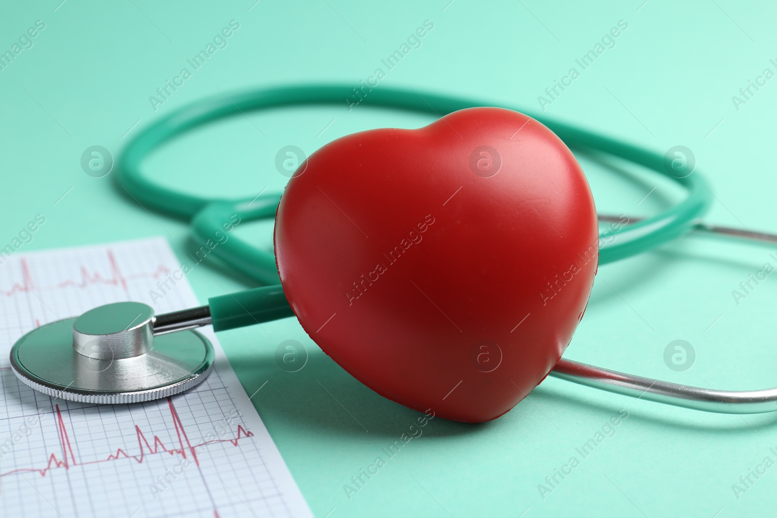 Photo of Cardiology. Stethoscope, cardiogram and red decorative heart on turquoise background, closeup