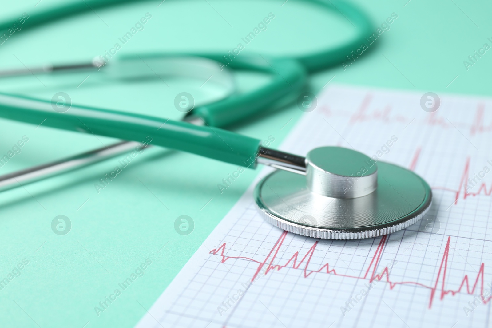 Photo of Cardiology. Stethoscope and cardiogram on turquoise background, closeup