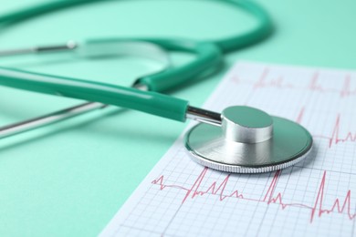 Photo of Cardiology. Stethoscope and cardiogram on turquoise background, closeup