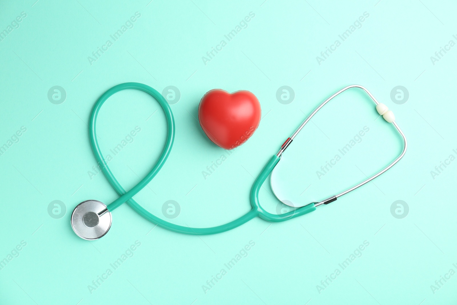 Photo of Cardiology. Stethoscope and red decorative heart on turquoise background, flat lay