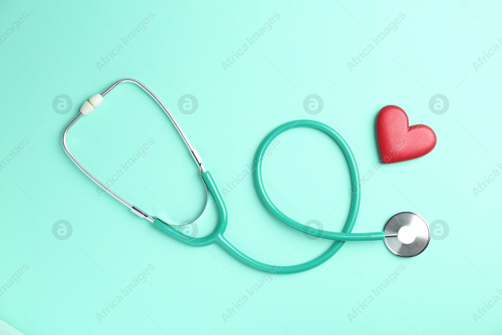 Photo of Cardiology. Stethoscope and red decorative heart on turquoise background, flat lay